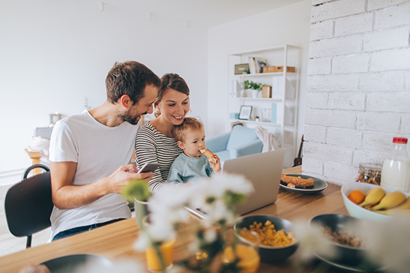 A family of three browsing on a laptop on at a dining table