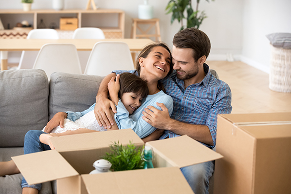 a father mother and child hugging while laying on a couch