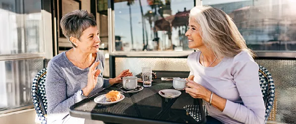 two women sitting outside on patio having coffee