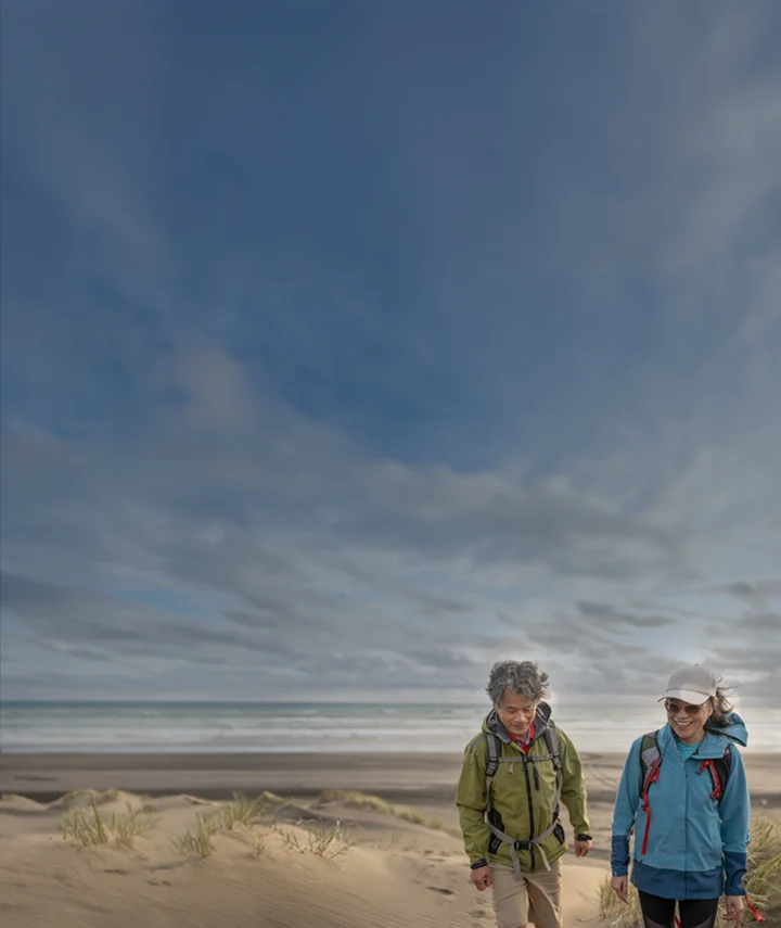couple in windbreaker jackets walking on beach