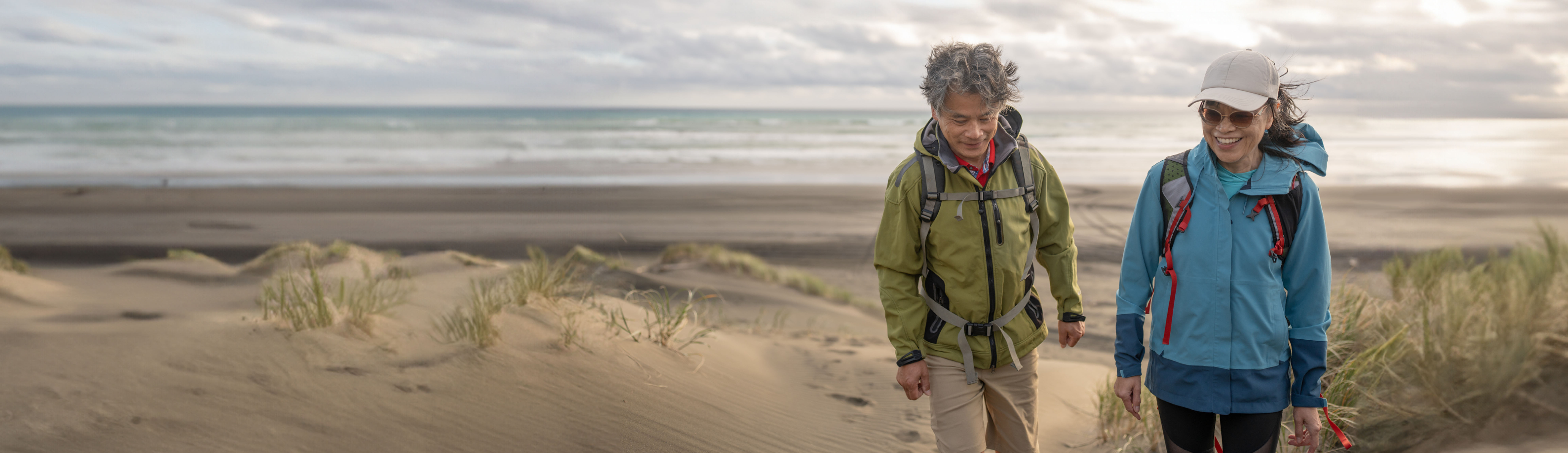 couple in windbreakers walking along beach