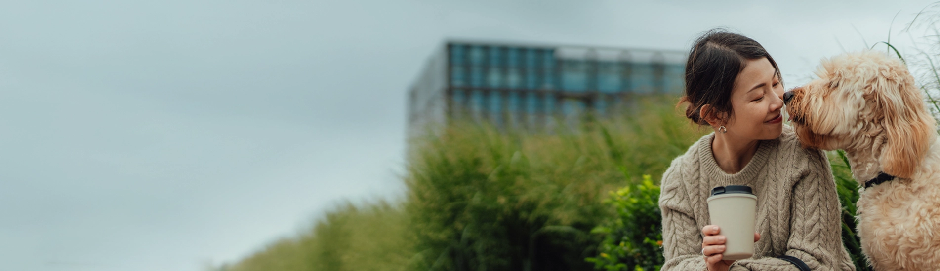 an Asian woman in her 30s leaning in to speak to her fluffly white dog